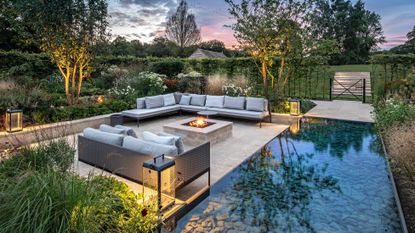 garden water feature and patio area lit at nightime