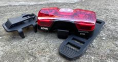 The Zefal Supervision R150 rear light with both the clip and band mount next to it displayed on a stone surface