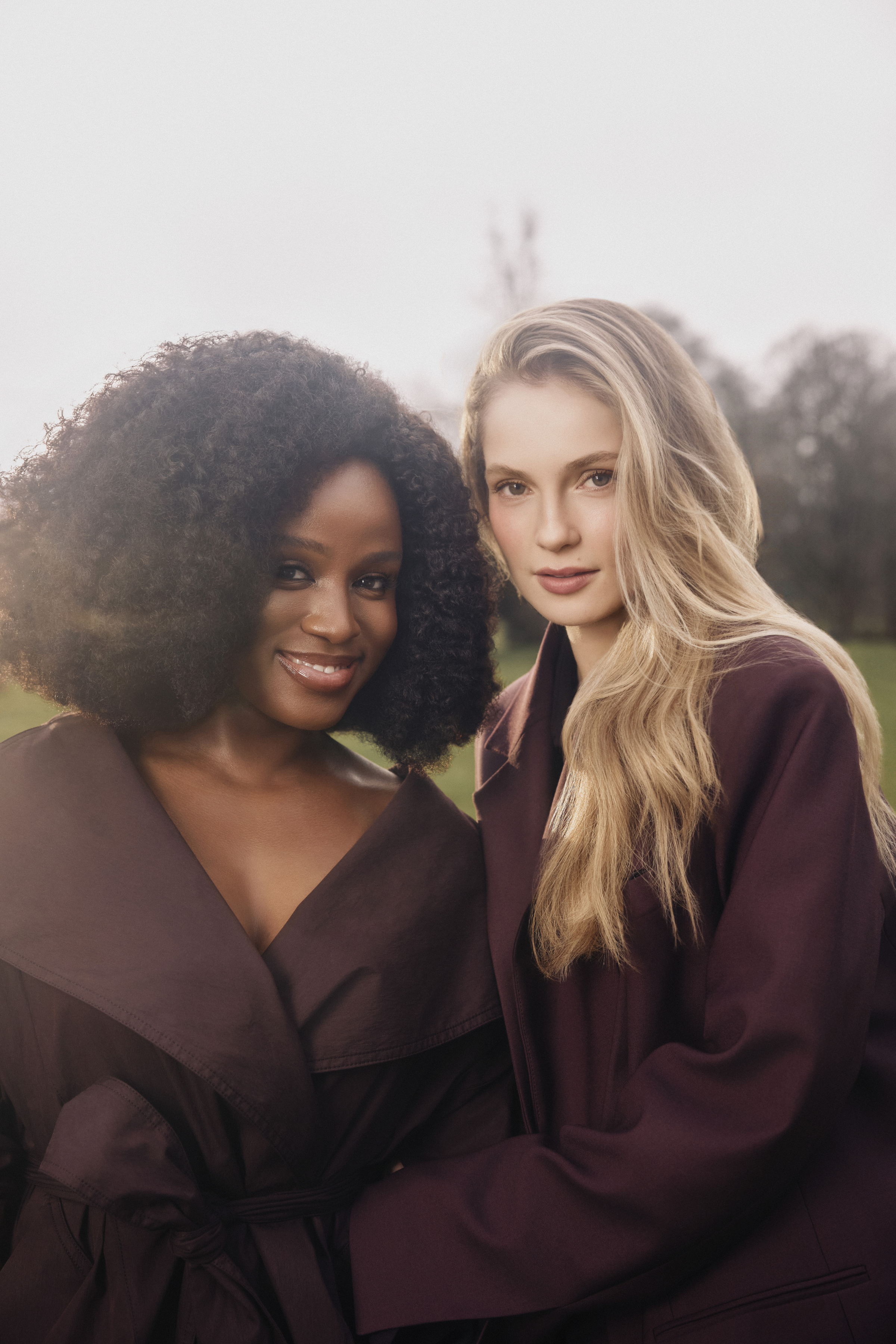 bridgerton stars Masali Baduza and Hannah Dodd of pose together wearing brown dresses in a field as production begins on season 5
