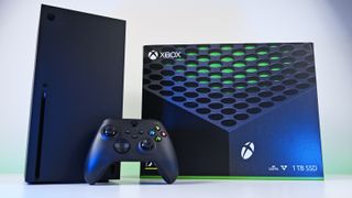 Front view of an Xbox Series X console and wireless controller next to the official retail packaging box under clean, bright studio lighting.