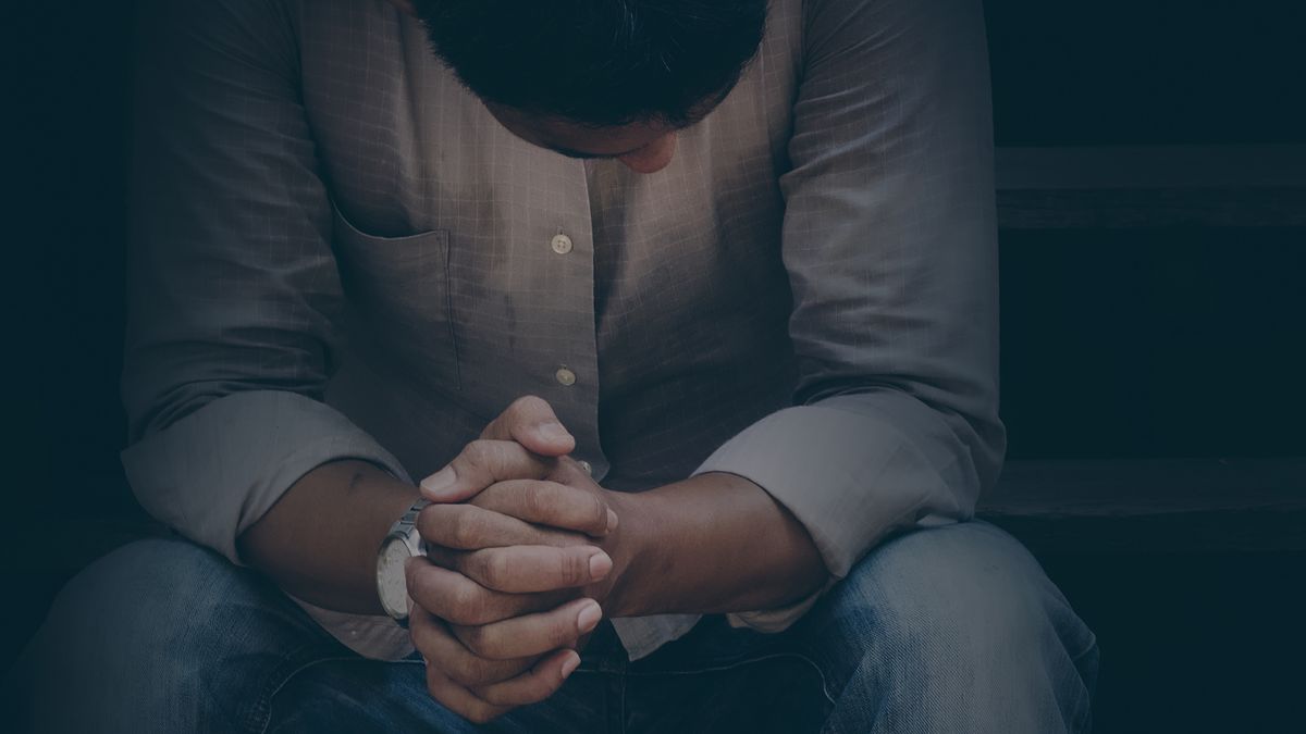 Depressed man sitting with hands folded