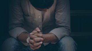 Depressed man sitting with hands folded