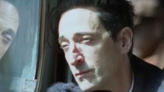 Adrien Brody riding in a bus in The Brutalist