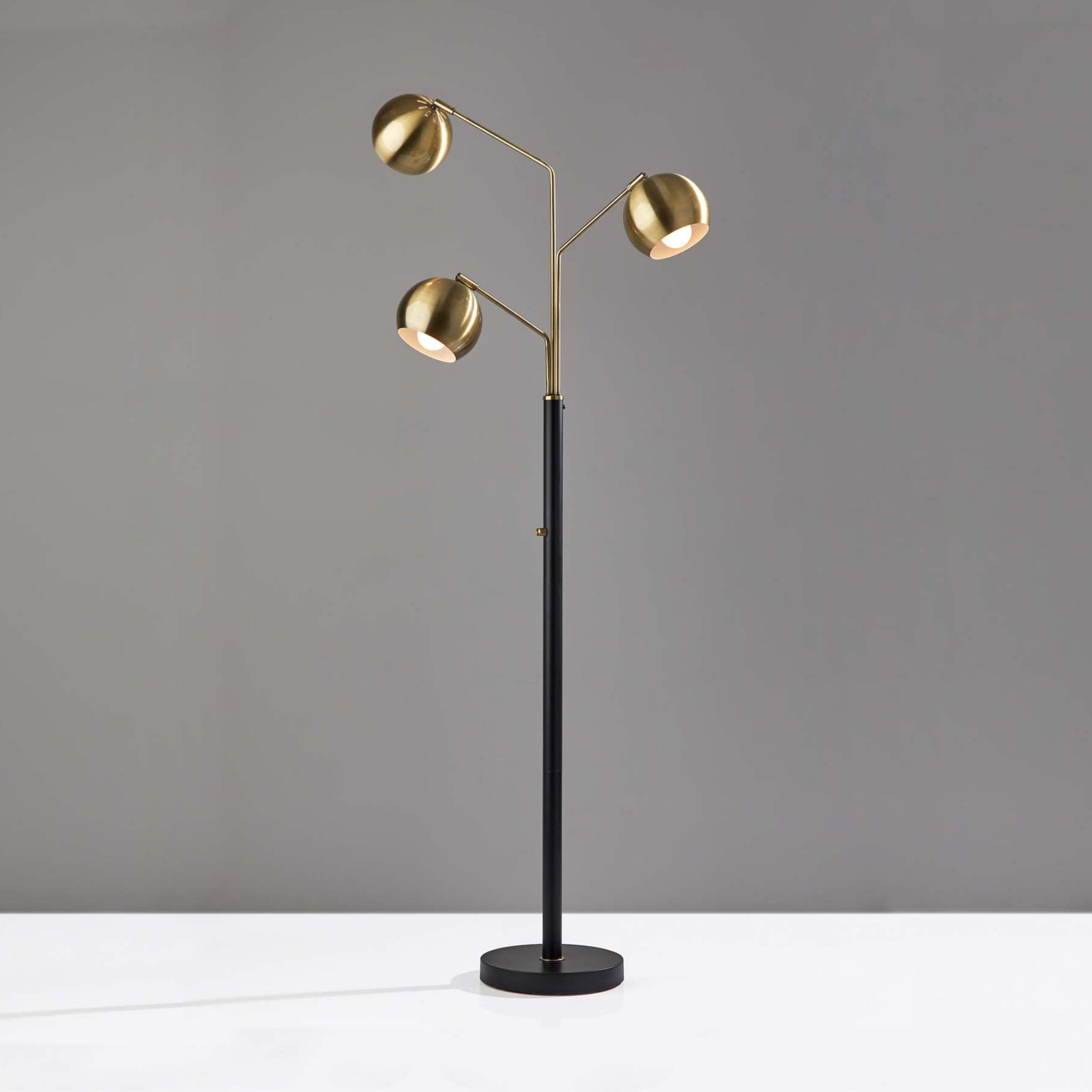 Black floor lamp with triple-head brass bulbs