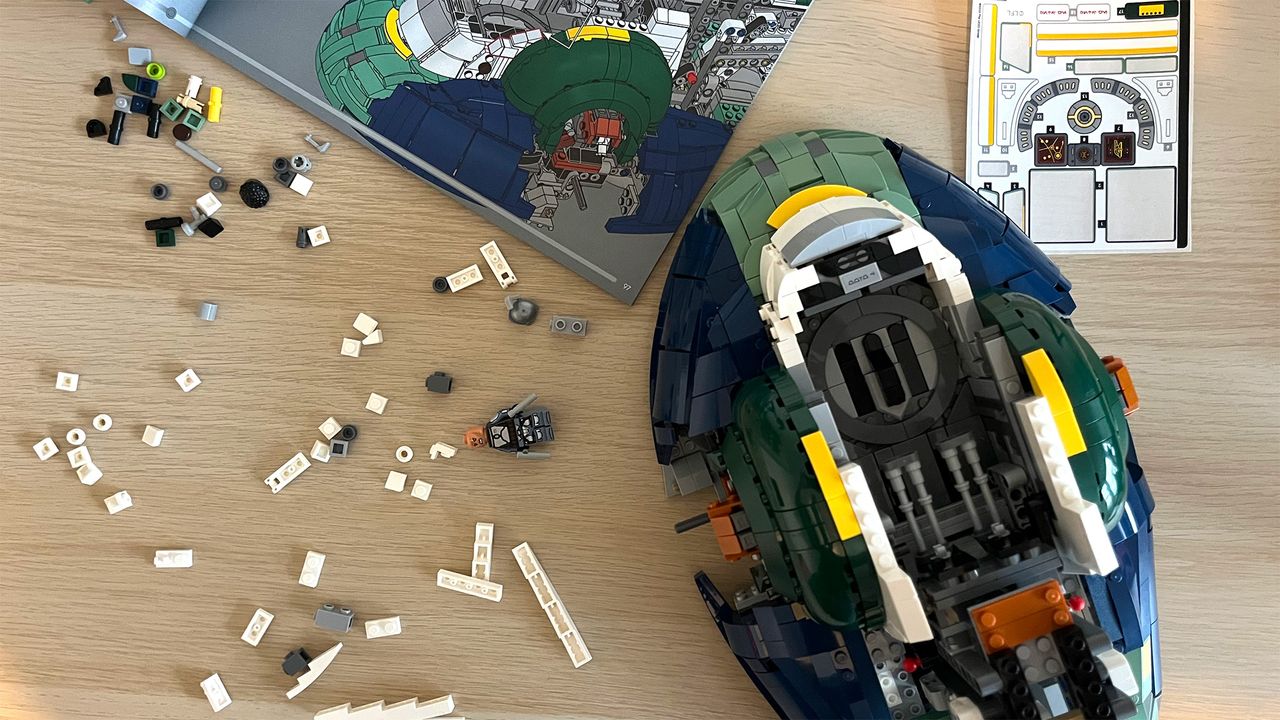 Lego Star Wars UCS Jango Fett&rsquo;s Firespray-Class Starship (75409) mid-build on wooden tabletop next to lots of Lego pieces and an instruction booklet