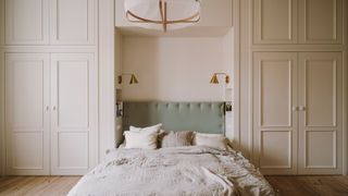 A bedroom with cream walls and sage headboard