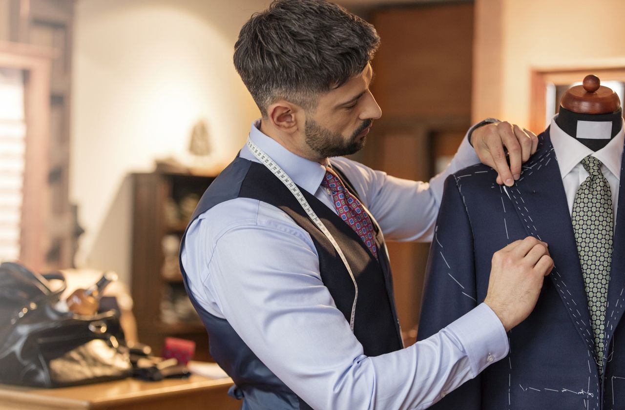 Tailor adjusting suit on dressmakers model in menswear shop