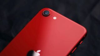 En närbild på kameramodulen på baksidan av en röd iPhone SE från 2022.