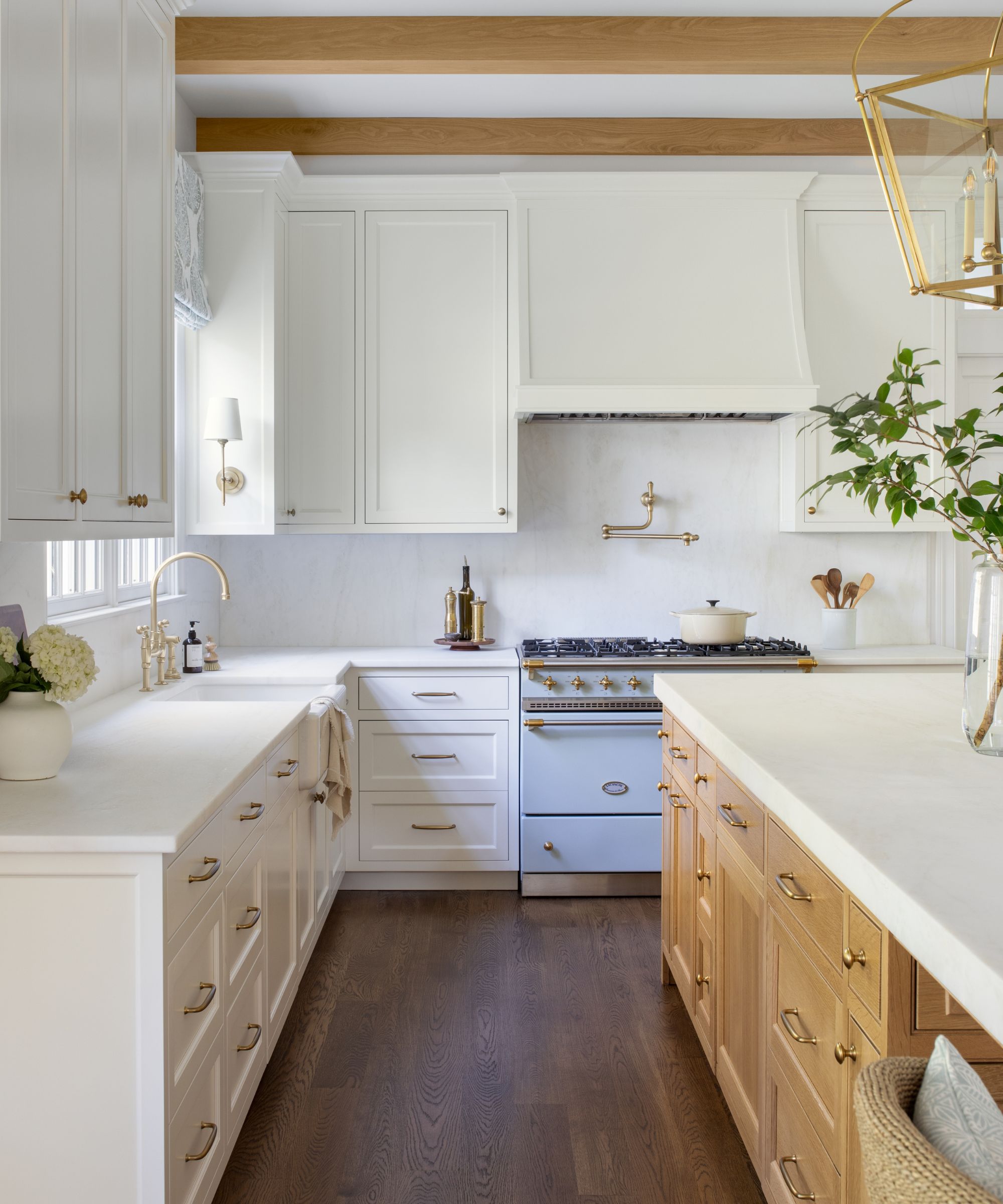 A white kitchen with a wood island and brass hardware