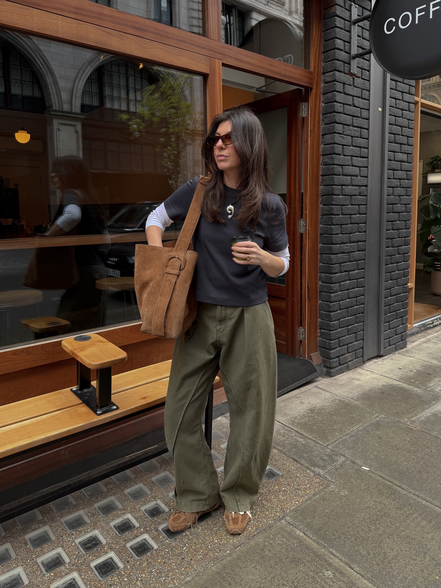 Francesca wearing a black top, khaki jeans and brown suede trainers