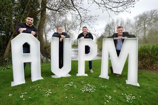 The AVPM Group employees standing by its large letters.