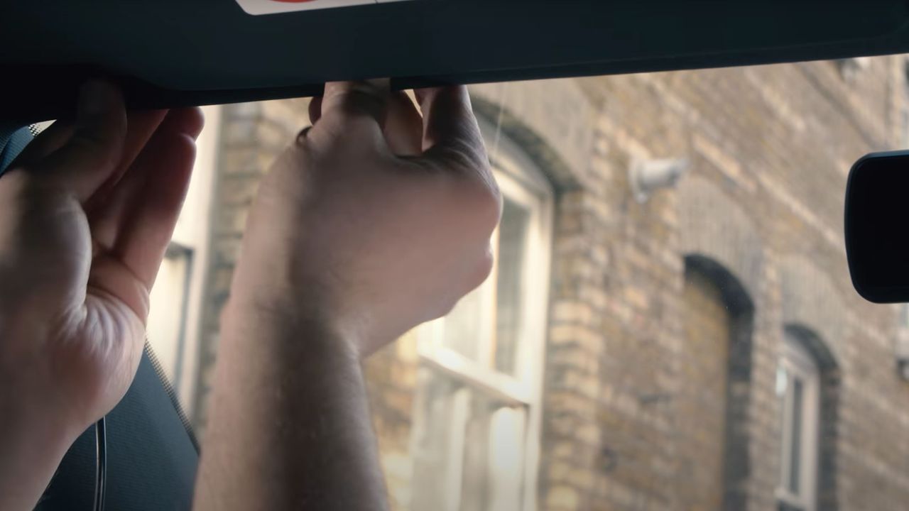 Some hands installing the a dash cam cable inside a car