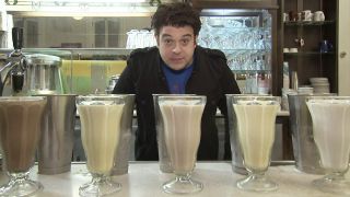 Adam Richman standing in front of a bunch of milkshakes