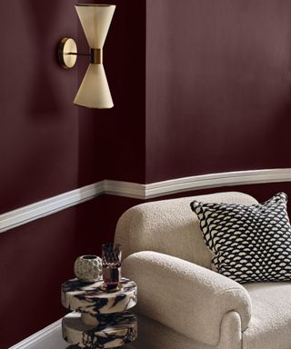 sitting room with dark purple walls, white picture rail, beige boucle chair and black and white patterned cushion