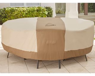 A piece of outdoor furniture on stone slab patio covered with taupe/brown protective cover