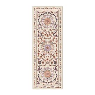 A rectangular beige rug with a decorative purple pattern on it