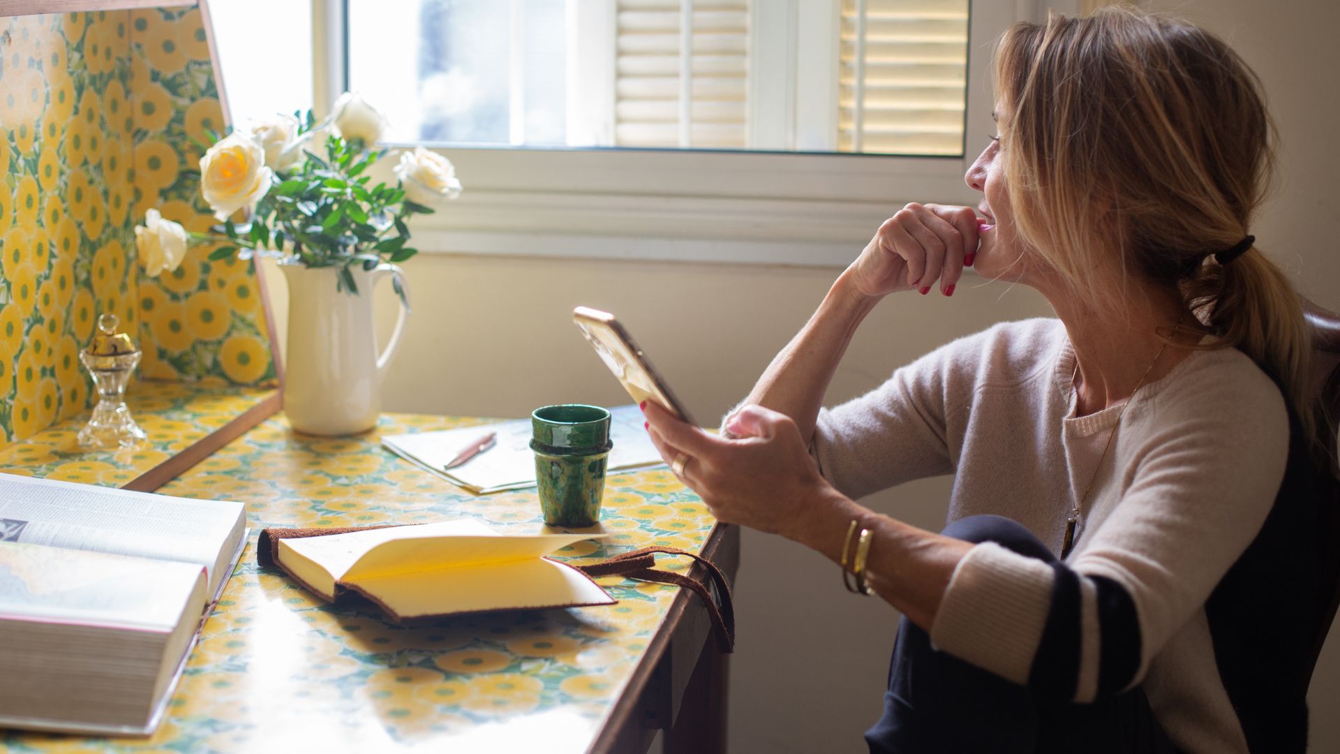 Woman sitting at desk writing goals down on phone