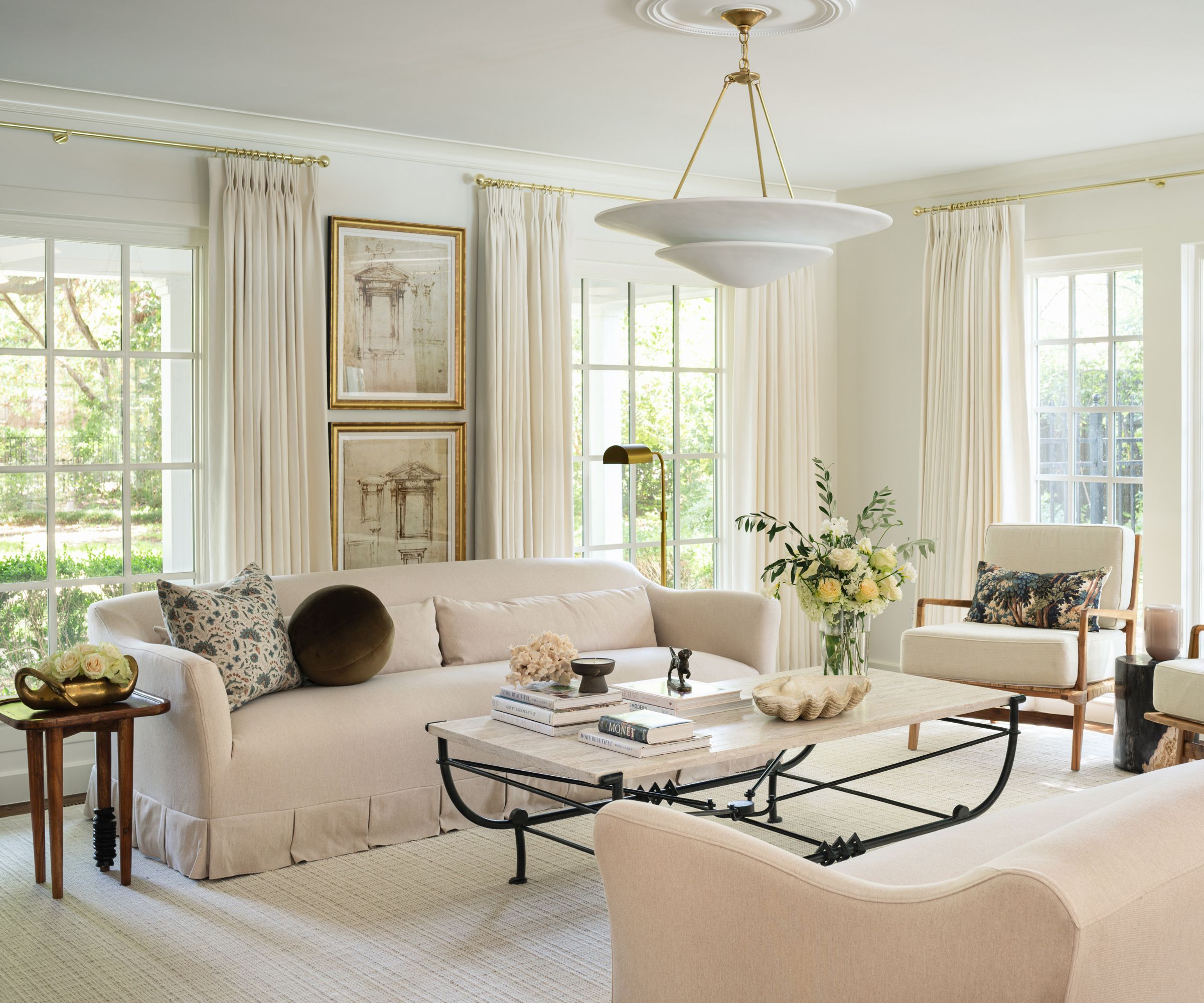 warm minimalist living room with all neutral decor, a wrought iron coffee table, arm chairs with foliage printed cushions and a skirted couch