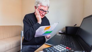 Worried senior man checking bills at home