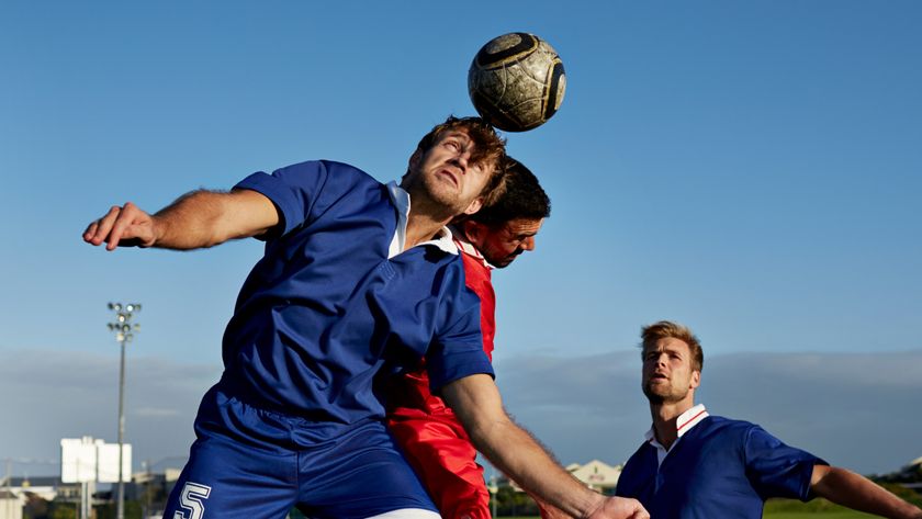 Two soccer players battling to head the ball