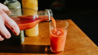 Woman's hand pouring smoothie from bottle in glass