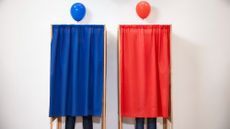 Voters voting in polling place. One is hidden behind red curtain with red balloon on top, and one is standing behind blue curtain with blue balloon.