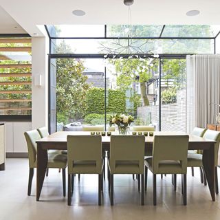 Glazed extension with glass roof, large sliding doors and dining room table in the centre