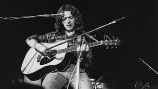 Irish guitarist and songwriter Rory Gallagher performing with an acoustic guitar, circa 1975.