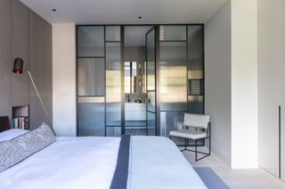 Bedroom with bed, floor lamp and view through to wardrobe with glass doors