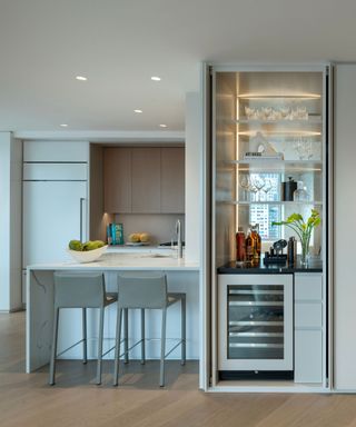 A modern kitchen with a storage island and two gray barstools