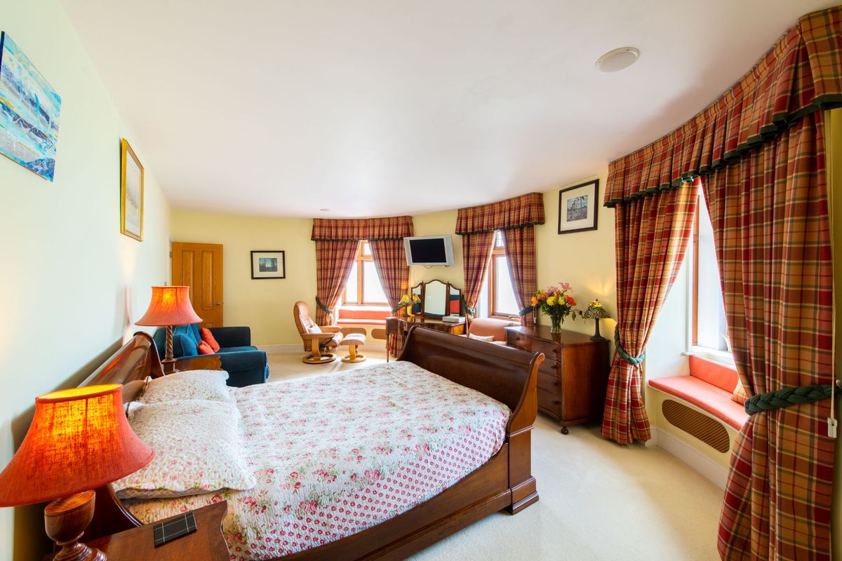 Bedroom with three window sills, tv and en suite and lean back leather chair in the corner
