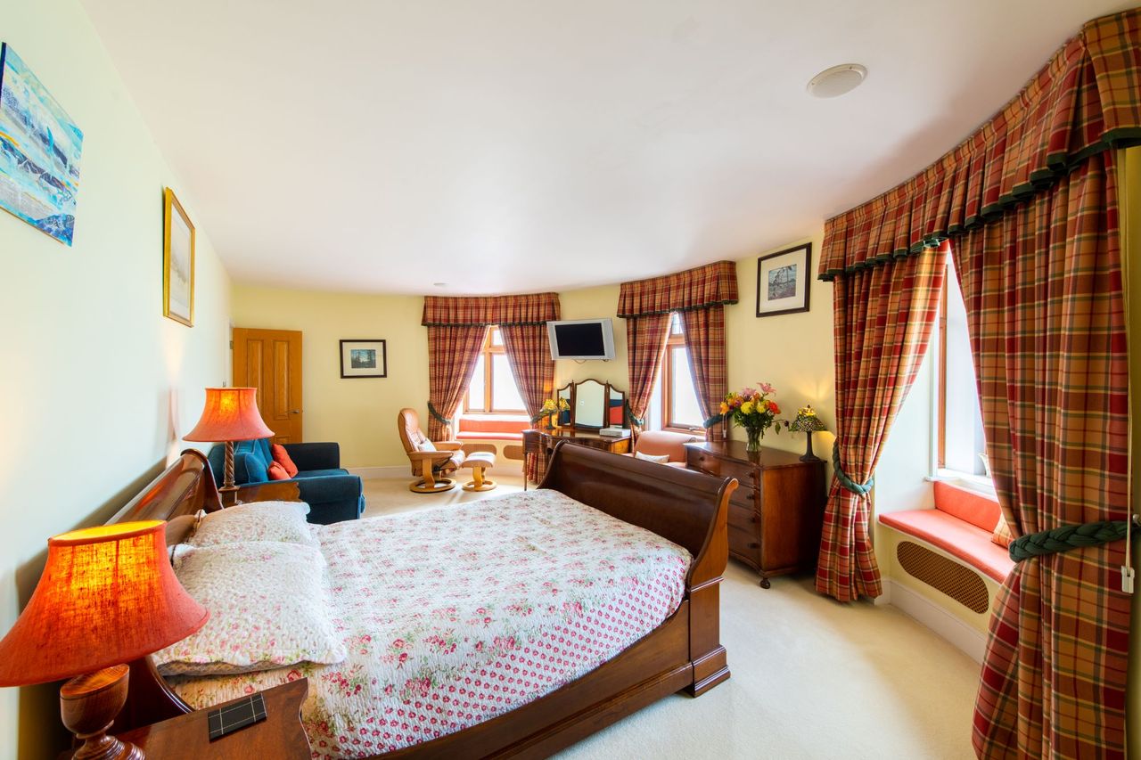 Bedroom with three window sills, tv and en suite and lean back leather chair in the corner