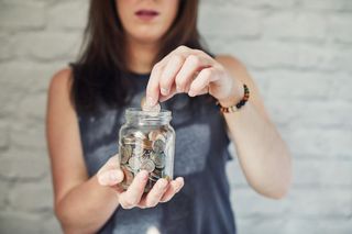 Young woman putting money into a jar