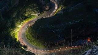 A close up of the road at Cheddar Gorge at night showing the headlights and brakelights trailing through the scene with a long exposure