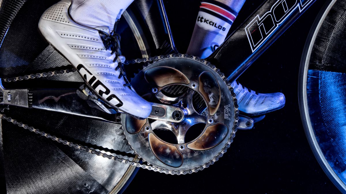 A close up of a mirror polished 5 arm crankset, propelled by a white Giro shoe