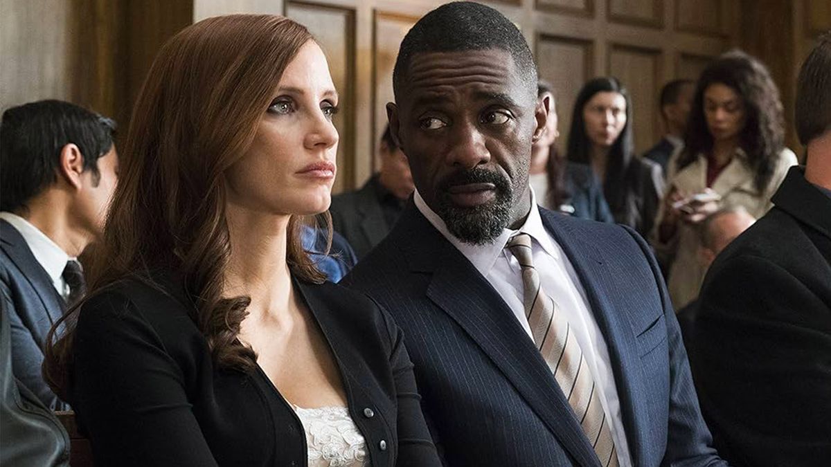 A still from the movie Molly&#039;s Game of two people sat beside in court