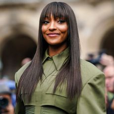 Jourdan Dunn smiling at Paris Fashion week in a green dress and long straight hair with a fringe