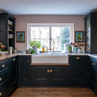 view onto fluted belfast sink in a small kitchen with dark green cabinets