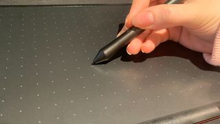 The stylus for the One by Wacom held in hand, in use on the tablet