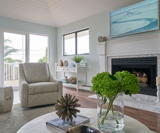 Coastal decor in a living room, featuring subtle blue walls and a chair upholstered in striped fabric