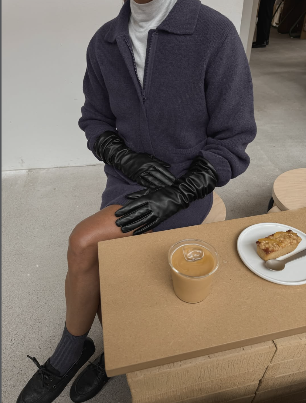 woman sitting at a table wearing long black leather gloves