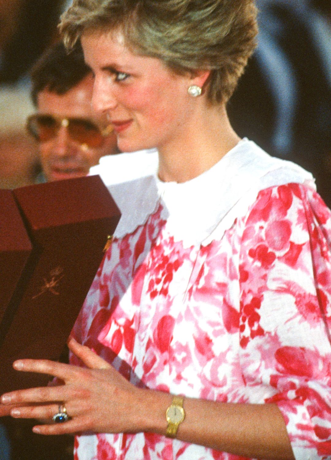 Princess Diana holding a box, with her gold watch visible