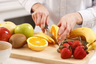 A woman cuts up fruit