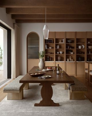 a dark wood table with two benches with wooden shelving behind