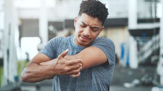 Man holding his elbow during a gym workout