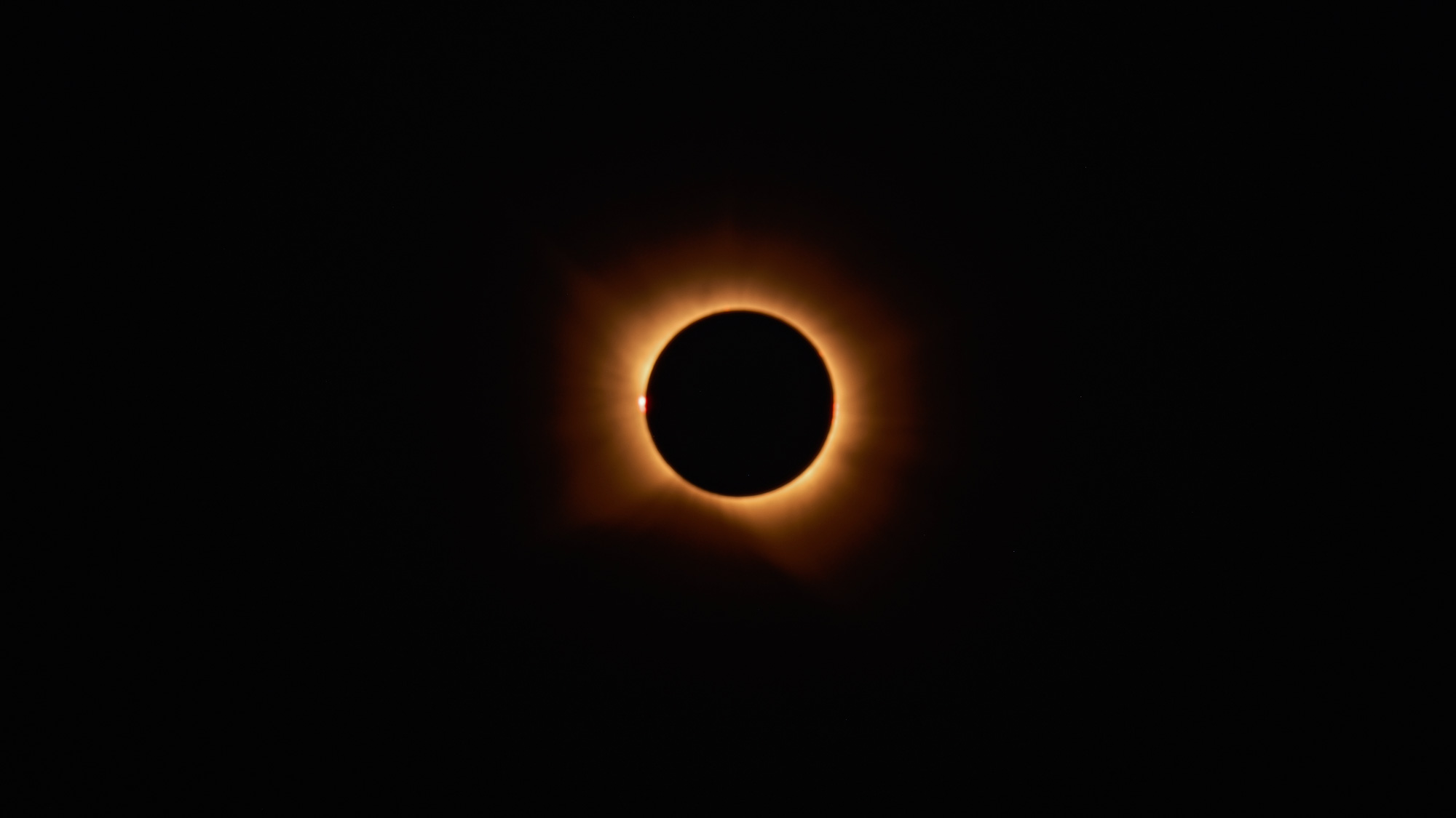 A fully eclipsed sun is photographed in a black sky.