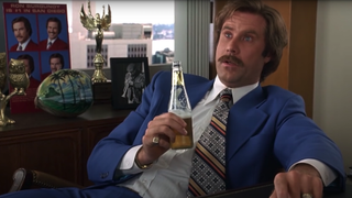 Ron Burgundy (Will Ferrell) sits at his desk holding a beer in Anchorman