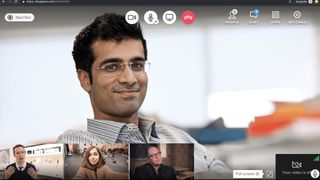 Man talking to 3 others in small-screen windows using videoconferencing