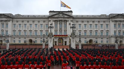 Exterior of Buckingham Palace with red uniformed guards standing outside