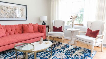 living room with coral sofa blue vintage rug and two white armchairs
